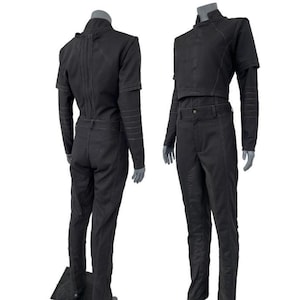 Peut inclure: Ensemble noir en deux pièces sur un mannequin. Le haut est une veste à col montant et à manches courtes avec une taille courte. Le pantalon est taille haute avec une coupe droite. L'ensemble a des détails de couture visibles et est fait d'un tissu foncé.