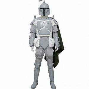 May include: A full-body suit of light grey armour featuring a helmet with a T-shaped visor and a rangefinder antenna. The ensemble includes chest plates, shoulder pauldrons, gauntlets, leg greaves, and a dark green cape attached to the left shoulder.