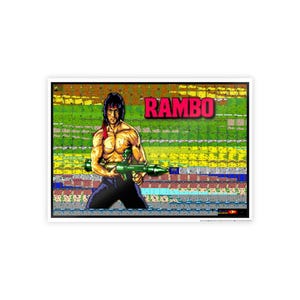 May include: A framed print featuring a pixelated image of a muscular figure holding a green rocket launcher. The word "RAMBO" is displayed in red block letters above the figure. The background is a colorful, pixelated design.
