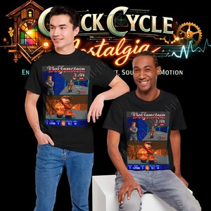 May include: Two people wearing black t-shirts featuring a retro video game graphic. The graphic includes the game title "Wolfenstein 3D" and pixelated characters. The shirts are paired with blue jeans.