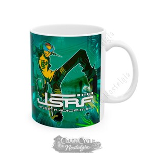 May include: A white ceramic mug featuring a vibrant teal and green graphic of a character wearing goggles and a yellow shirt. The design includes the text JSRF JET SET RADIO FUTURE in bold white lettering, set against a stylized urban background.