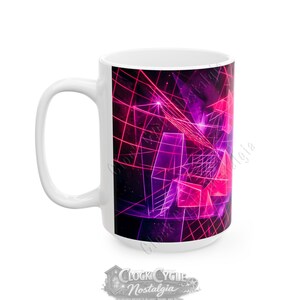 May include: White ceramic mug featuring a vibrant, geometric design in shades of pink and purple. The design includes a grid pattern and abstract shapes, creating a retro-futuristic aesthetic. The mug has a large handle and a glossy finish.