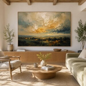 May include: A large rectangular landscape painting featuring a dramatic sky with golden and white clouds above a dark green horizon. The artwork is displayed on a white wall above a long wooden slatted console table in a bright living room.