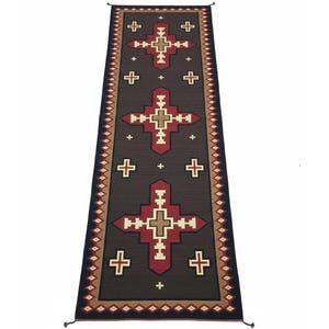 May include: A long, rectangular rug with a dark brown background and a repeating pattern of crosses in red, tan, and white. The edges feature a decorative border with geometric shapes and tassels at the ends. The rug is designed for a hallway or entryway.
