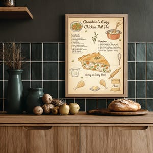 Könnte beinhalten: Ein gerahmter Druck mit dem Rezept für "Omas gemütlichen Hühner-Topf-Kuchen". Die Illustration zeigt ein Stück Kuchen, Zutaten und Anweisungen. Der Druck befindet sich auf einer Holzoberfläche, zusammen mit einem Brotlaib und dekorativen Vasen.