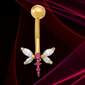 May include: Gold-coloured belly button ring with a dragonfly design. The dragonfly features white and pink gemstones. The top ball and the post are gold. The gemstones are set in a symmetrical pattern, creating a delicate piece of jewellery.
