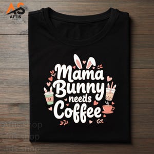 Peut inclure: T-shirt noir avec l'inscription blanche "Mama Bunny needs Coffee", entourée de cœurs roses et de feuilles vertes. Le motif comprend des oreilles de lapin, des tasses à café et une tasse de thé.