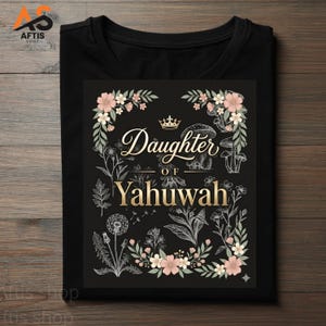 Peut inclure: T-shirt noir avec l'inscription dorée "Daughter of Yahuwah", entourée de motifs floraux et botaniques blancs et roses. Une couronne surmonte le texte. Le t-shirt est à col rond.