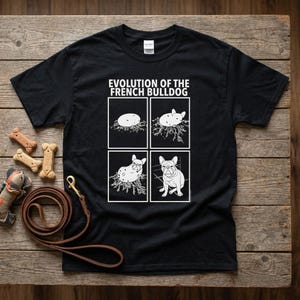 Könnte beinhalten: Ein schwarzes Kurzarm-T-Shirt mit einem weißen Grafikdruck mit dem Titel "EVOLUTION OF THE FRENCH BULLDOG" und vier Feldern, die die Entwicklung einer Kartoffel zu einer Französischen Bulldogge zeigen, inklusive Hundeleine und Leckerlis.