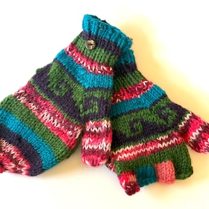 May include: A pair of knitted mittens in a vibrant colour palette. The mittens display a pattern of stripes and geometric designs in blue, green, pink, and purple. A button fastens the cuff of one mitten. These mittens are designed for warmth and fashion.