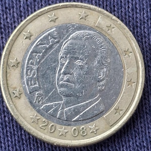 Könnte beinhalten: Eine Ein-Euro-Münze mit einem goldfarbenen Außenring und einem silberfarbenen Mittelteil. Die Münze zeigt ein Porträt eines Mannes und das Wort "ESPAÑA" am Rand. Das Jahr "2008" ist ebenfalls sichtbar.