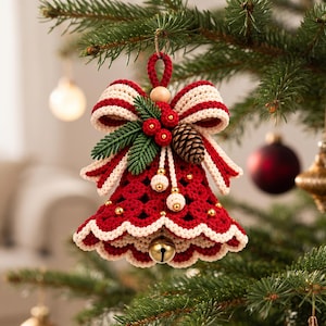 May include: A crocheted Christmas bell ornament in deep red with a cream-coloured scalloped edge. The top features a large cream and red striped bow, green pine needles, red berries, a small pinecone, and a gold jingle bell hanging inside.