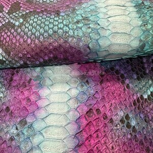 May include: Detailed view of a snakeskin pattern in purple, pink, teal, and grey. The scales are clearly defined, creating a textured surface. This material is suitable for fashion items or interior design projects.