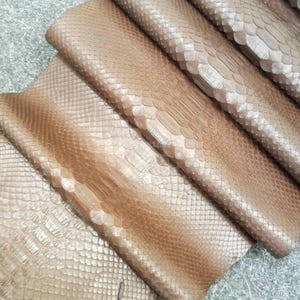 Puede incluir: Un juego de tres tazas de cerámica con un acabado mate moteado. Las tazas son de color crema, gris claro y gris oscuro. Cada taza tiene un diseño simple y minimalista y un asa redondeada.