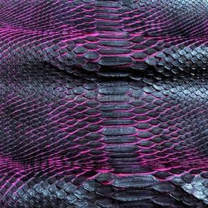 Op de afbeelding: Close-up van een gestructureerd oppervlak dat op slangenleer lijkt. De schubben zijn donker houtskoolkleurig met levendige magenta accenten ertussen. Het patroon is gedetailleerd en creëert een visueel opvallend effect.