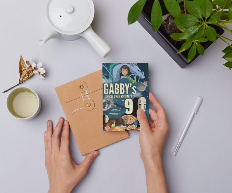 K&ouml;nnte beinhalten: Eine Person h&auml;lt eine farbenfrohe Einladungskarte mit dem Text "Gabby's Spirited Away Adventure 9". Die Karte zeigt Illustrationen aus dem Animationsfilm. Ein brauner Umschlag, eine wei&szlig;e Teekanne und eine Tasse Tee sind ebenfalls zu sehen.