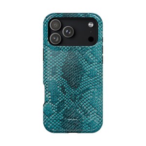 May include: A smartphone case featuring a teal and black snakeskin pattern with a textured scale design. The case has a cutout for a triple-lens camera system and a flash. The word monstera is printed in small white letters near the bottom edge.