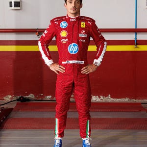 May include: A red racing suit with sponsor logos, white accents, and blue shoes. The suit features the number 16 and the name "Charles Leclerc". The suit has a quilted pattern and Italian flag stripes on the legs.
