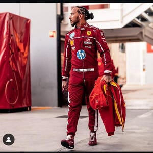 May include: A maroon racing suit with white stripes and sponsor logos. The suit has the number 44 and the name "LEWIS HAMILTON". The person is holding a matching jacket and bag. The person is wearing maroon sneakers.