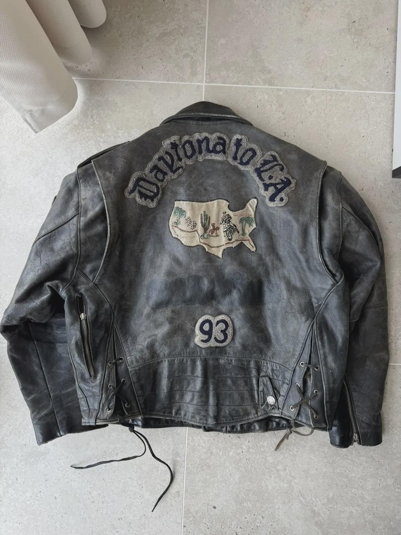 May include: Distressed black leather jacket with the text "Daytona to L.A." and a map graphic on the back. Features a "93" patch and side lacing details. A vintage-style motorcycle jacket.