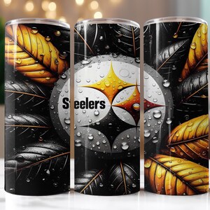 Op de afbeelding: Een roestvrijstalen beker met het logo van de Pittsburgh Steelers op een zwart-witte achtergrond. Het ontwerp bevat gele en gouden bladeren met waterdruppels. Het woord "Steelers" staat op de beker.