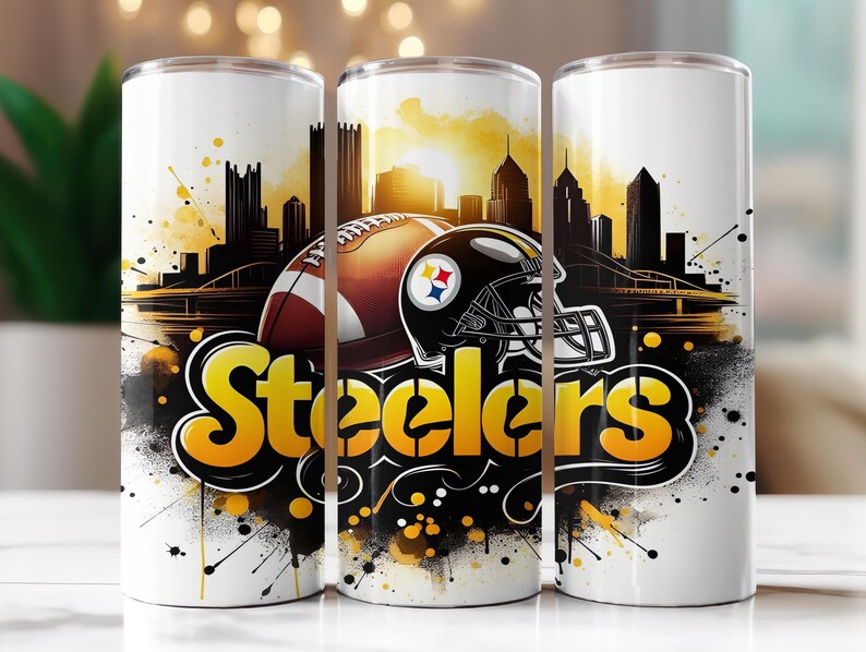 Op de afbeelding: Witte tumbler met een voetbal, helm en het woord "Steelers" in geel en zwart. Het ontwerp bevat een silhouet van een stadsgezicht en abstracte verfspatten, wat een dynamische sportthema-esthetiek cre&euml;ert.