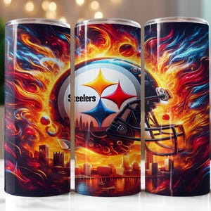 Op de afbeelding: Drie roestvrijstalen bekers tonen het logo van de Pittsburgh Steelers, een voetbalhelm en een stadsgezicht. De achtergrond toont vurige kleuren van rood, oranje en blauw, wat een dynamische en opvallende esthetiek cre&euml;ert.