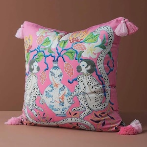 Può includere: Cuscino decorativo rosa con una vivace illustrazione di scimmie, fiori e un vaso. Il cuscino presenta uno sfondo rosa con scimmie maculate bianche e nere ed è adornato con nappe rosa su ogni angolo.