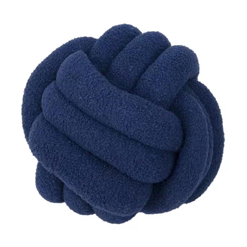 Op de afbeelding: Een donkerblauw knoopkussen in een bolvorm, gemaakt van een doorlopende, pluche en getextureerde stoffen buis die is geweven in een complex, meerlaags knooppatroon. Het oppervlak heeft een zachte, pluizige uitstraling in marineblauw.