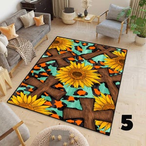 May include: A rectangular rug with a turquoise background and orange and black leopard print spots. Large brown crosses and yellow sunflowers are printed on the rug. The rug has a black border and is placed on a light wood floor.