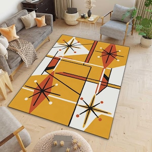 May include: A rectangular area rug with a mid-century modern design. The rug features a geometric pattern with starbursts, diamonds, and lines in orange, black, red, and white. The rug is bordered in black and is placed on a light wood floor.