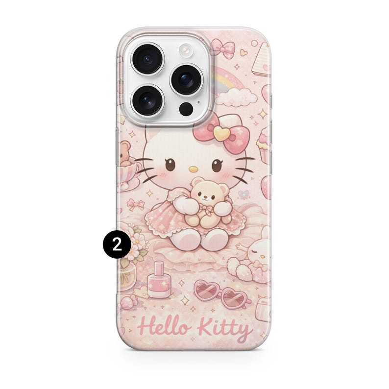 May include: A pink phone case with a Hello Kitty design, holding a teddy bear, and other illustrations. The case has a clear border and the words "Hello Kitty" at the bottom. The design includes a bow and a rainbow.