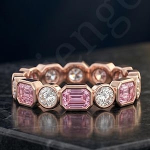 Könnte beinhalten: Ein Ewigkeitsring aus Roségold mit einem abwechselnden Muster aus in Zargenfassung gesetzten smaragdgeschliffenen rosa Edelsteinen und runden, brillantgeschliffenen klaren Edelsteinen. Der Ring zeigt ein durchgehendes Design in Metallfassungen.