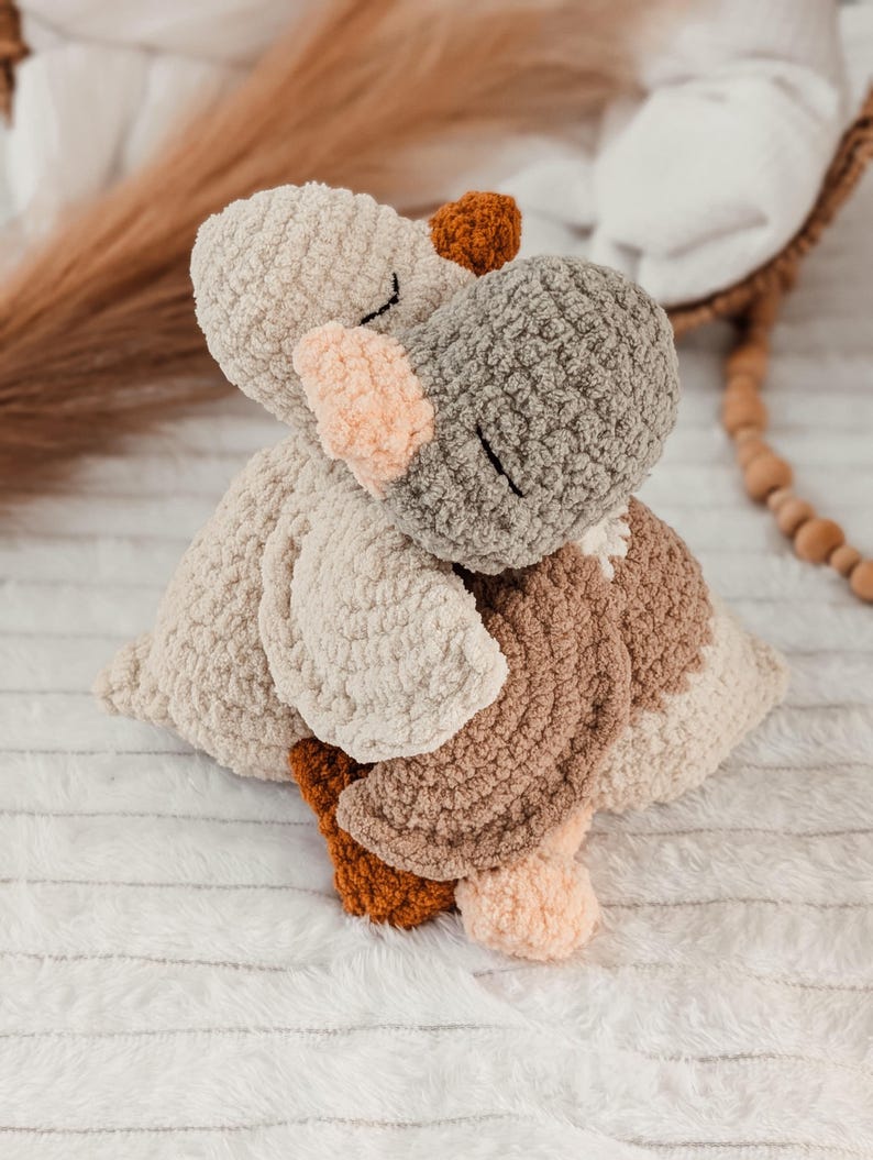 Puede incluir: Un juguete de hipop&oacute;tamo de peluche hecho a mano en tonos beige, gris, marr&oacute;n y melocot&oacute;n. El hipop&oacute;tamo est&aacute; tejido con un hilo suave y texturizado, con los ojos cerrados y un dise&ntilde;o suave y abrazable. El juguete est&aacute; sobre una superficie blanca y texturizada.