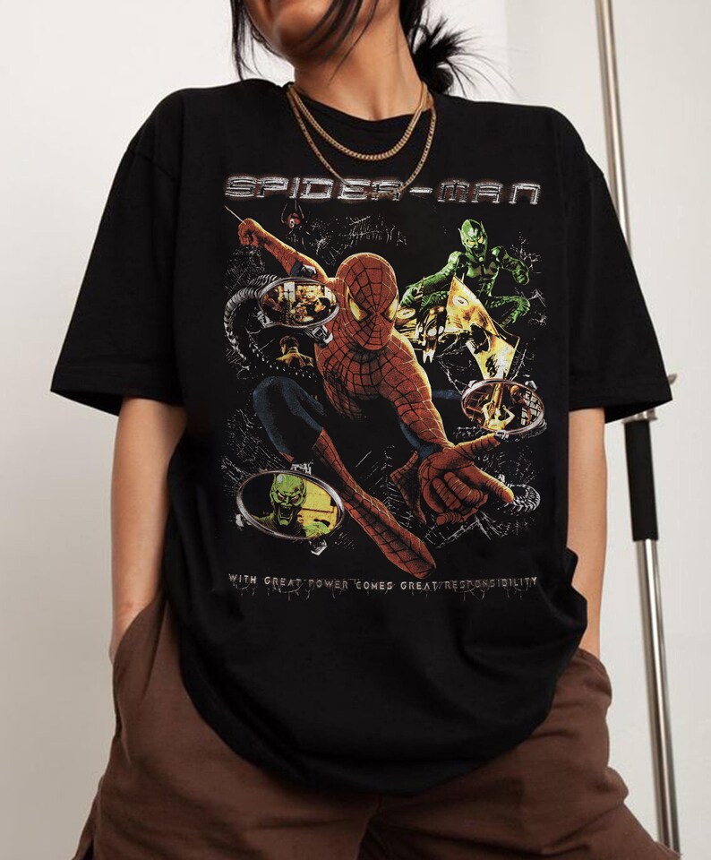 May include: Black Spider-Man t-shirt featuring a graphic of Spider-Man in action with the Green Goblin. The shirt has the text "SPIDER-MAN" and "WITH GREAT POWER COMES GREAT RESPONSIBILITY".
