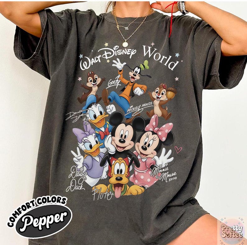 May include: Dark grey t-shirt featuring a graphic of Disney characters including Mickey Mouse, Minnie Mouse, Donald Duck, and Goofy. The shirt has the text "Walt Disney World" and character signatures. The shirt is labeled "Comfort Colors Pepper".
