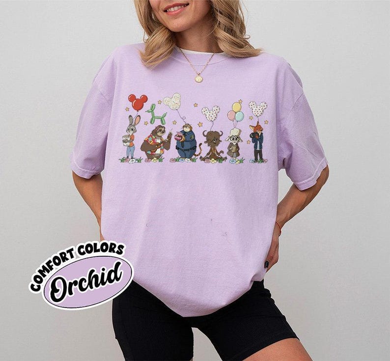 Puede incluir: Una camiseta lila Comfort Colors con una ilustraci&oacute;n caprichosa de animales de dibujos animados sosteniendo ramos de globos. La camiseta tiene el texto "Orchid" en la parte delantera. El dise&ntilde;o incluye un conejo, un perezoso, un oso, un toro, un ciervo y un zorro.