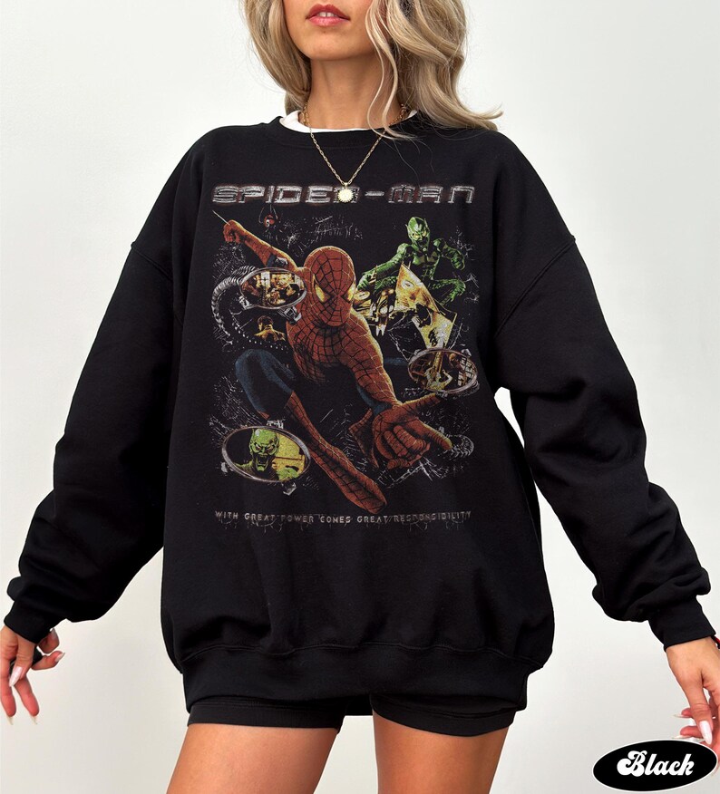 May include: Black Spider-Man sweatshirt featuring a graphic of Spider-Man and the Green Goblin. The text "SPIDER-MAN" is across the top, and "WITH GREAT POWER COMES GREAT RESPONSIBILITY" is below the graphic. The word "Black" is at the bottom.