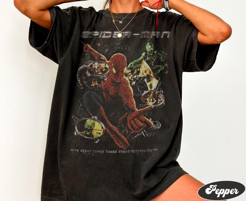 May include: Black t-shirt featuring a Spider-Man graphic. The design includes Spider-Man in action, the Green Goblin, and the text "SPIDER-MAN" and "WITH GREAT POWER COMES GREAT RESPONSIBILITY".