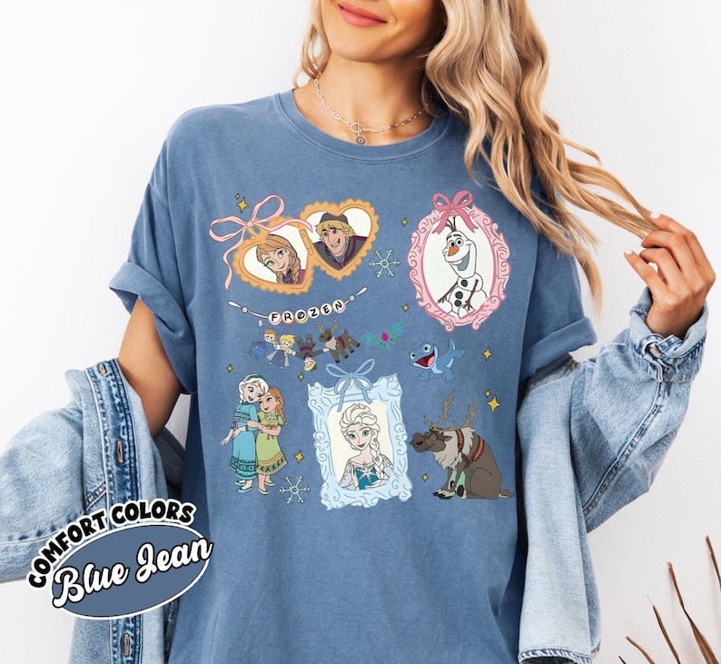 May include: Blue jean Comfort Colors t-shirt featuring framed illustrations of characters from the movie Frozen. The shirt includes images of Anna, Elsa, Olaf, Kristoff, and Sven. The word "Frozen" is also printed on the shirt.