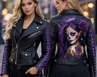 May include: Black leather jacket with purple accents on the sleeves and back. The jacket features silver studs on the shoulders and a graphic of a woman with sugar skull makeup and a black cat on the back. The AmeriGlo logo is visible.