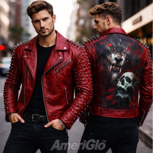 Peut inclure: Veste en cuir rouge ornée de pointes argentées sur les épaules et les manches. Le dos de la veste présente un motif de loup et de crâne. La veste a un style motard classique avec un col cranté et des détails de fermeture éclair. La marque "AmeriGlo" est visible en bas.