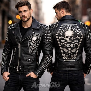 May include: Black leather jacket with silver stud detailing on the shoulders and sleeves. The jacket features a "Memento Mori" patch with a skull and crossbones design. The jacket has a zip closure and a belt.