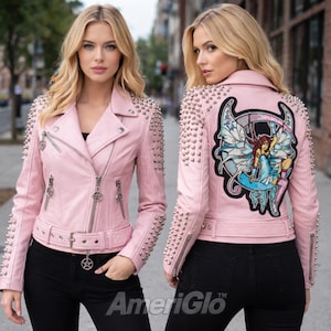 Op de afbeelding: Lichtroze leren jas met zilveren studs op de schouders en mouwen. De jas heeft een ritssluiting, een riem en een afbeelding op de rug. De tekst "AmeriGlo" is zichtbaar aan de onderkant.