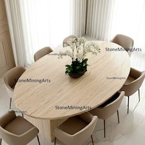 Puede incluir: Una mesa de comedor ovalada con una encimera de piedra beige claro, rodeada de ocho sillas tapizadas beige con patas de metal. Un arreglo floral se encuentra en el centro de la mesa. La habitación tiene piso de mármol blanco y paredes beige.