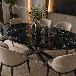 May include: An oval black marble dining table with white veining, surrounded by eight beige upholstered chairs. The table has a dark metal base. A vase with greenery sits on the table. The room has a neutral color palette.