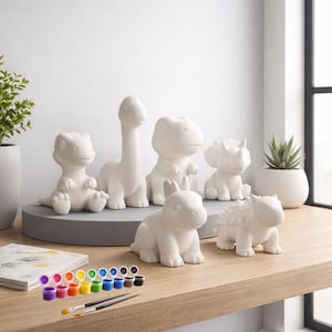 Puede incluir: Un conjunto de seis figuras de dinosaurios de cerámica sin pintar en varias poses. Incluye botes de pintura de múltiples colores y dos pinceles, listos para pintar. Los dinosaurios se exhiben en una estantería de madera.