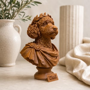Puede incluir: Un busto de color marr&oacute;n que representa a un perro de pelo rizado con una corona de laurel y una toga drapeada. La escultura incluye una peque&ntilde;a placa rectangular en la base con el texto Dhel grabado en letras de bloque en relieve.