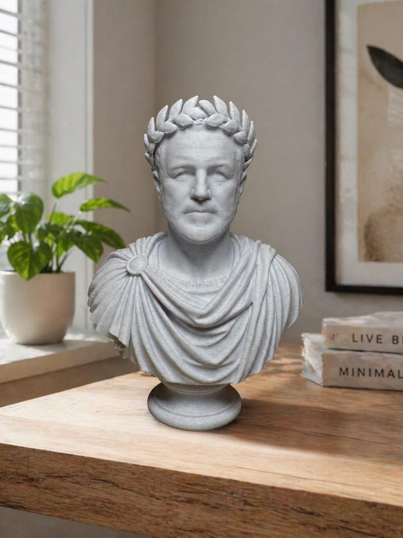 May include: A light gray bust of a Roman figure wearing a laurel wreath crown and a draped toga. The sculpture features detailed facial features, a circular brooch on the shoulder, and a pedestal base, crafted with a textured stone-like finish.