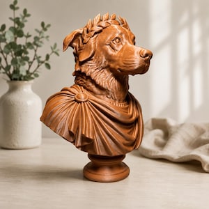 Puede incluir: Un busto de perro color terracota que lleva una corona de laurel en la cabeza y una prenda drapeada estilo toga sujeta con un broche circular en el hombro. La escultura est&aacute; montada sobre una base circular y presenta una textura de pelaje detallada.
